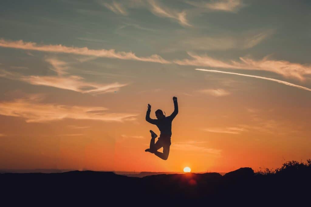 Man jumping high up in the air, sunset in the background.