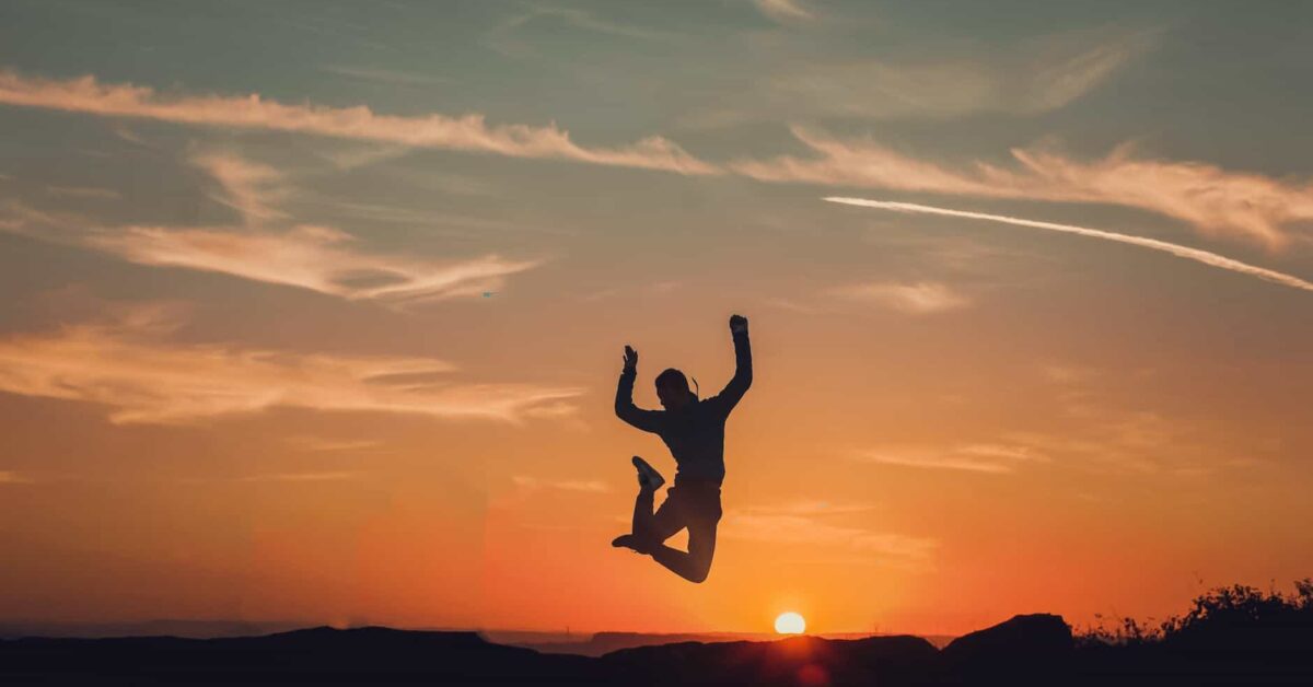 Man jumping high up in the air, sunset in the background.